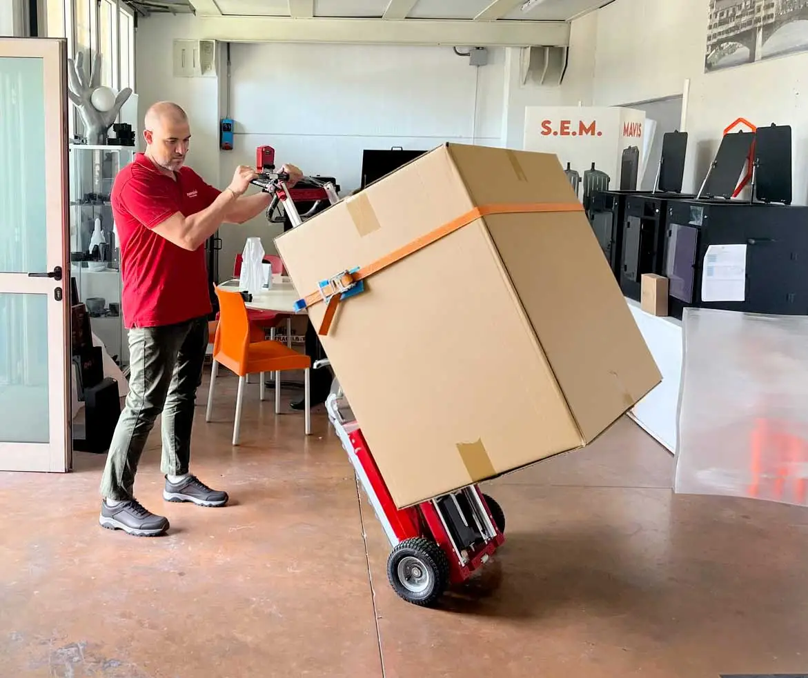 Un homme transporte un meuble emballé avec le monte-escalier électrique Buddy dans un entrepôt de marchandises