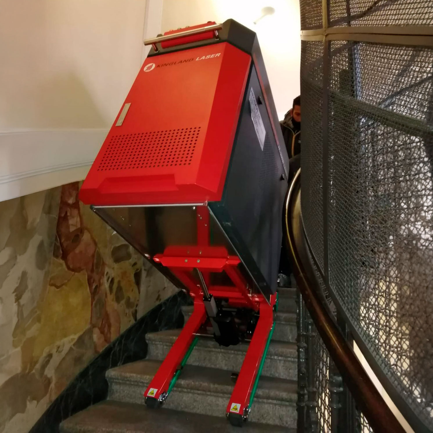 Trasporto di un macchinario Kingland sulla scala in marmo di un condominio con il carrello cingolato elettrico saliscale Domino